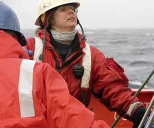 Marine Technician Jamee Johnson positions the MOCNESS frame in its cradle as the winch lowers it.