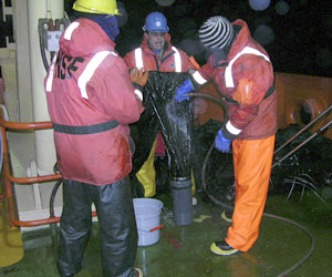After the night tow, Erich Horgan (blue hard hat) holds the net while Byron Pedler rinses the sample into its container.