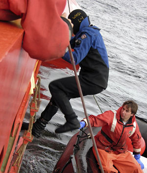 The dive boat rises and falls several feet continuously on swells, while the Gould rocks independently. It can be a dangerous climb down the ladder, and Brennan Phillips helps Byron Pedler step into the boat. (Photo K. Madin, WHOI) 