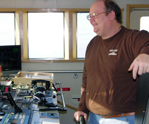 Larry Brissette, the third mate, keeps a hand on the wheel, on the bridge of the Gould. (Photo by Kate Madin, WHOI)