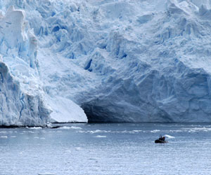 Researchers doing fieldwork in an inflatable boats glide past the glacier�s edge. (Photo by Byron Pedler, WHOI)