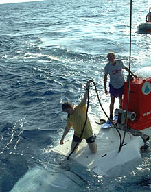 Dave Olds grabs the tail line as Alvin is prepared for recovery. Ken Kenerson waits by the sail to help out.