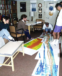 Chief Scientist Dan Fornari (far right) directs a meeting with his colleagues (from left, Maya Tolstoy, Rachel Haymon, Mike Perfit, kneeling, and Dan Scheirer) to discuss the plan for the first survey area on the East Pacific Rise between 9-10&deg;N latitude. Multibeam bathymetry maps laid out on the floor provide key information on the mid-ocean ridge crest's topography and structure, which guides scientists to sites of potential volcanic eruptions. 