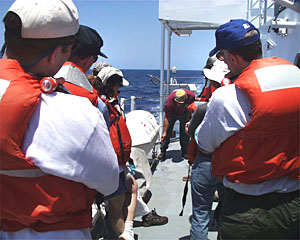 Dave Murline goes over procedures for releasing life boats from their protective cases, in the case of an emergency that requires abandoning ship. The life boats contain enough food, water and medical supplies to take care of people for seven days at sea.
