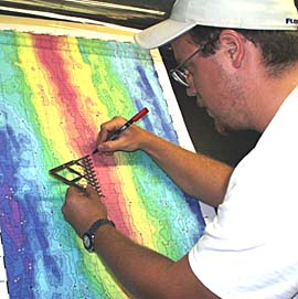 Erin Todd, a student from the University of Florida, plots the position of the DSL-120 sonar “fish” on the bathymetric map of the East Pacific Rise in the Control Van. We keep track of the sonar all the time to make sure we are surveying where we had planned, and to make sure we do not run the sonar “fish” into any volcanic cones sticking up from the seafloor. The crest of the Rise is shown by the red color on the map. Erin is using an instrument called a “ten point divider”. It can be expanded and contracted to fit any space, and then the “points” divide that space into ten equal parts.