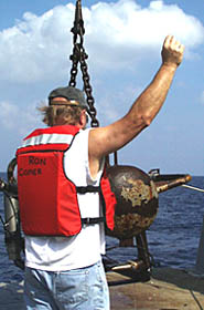 Ron Comer, Scripps’ resident technician, signals the winch operator as they bring the sonar clump weight on board.