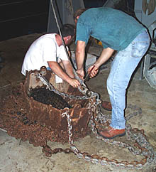 Ron Comer, the Scripps Resident Technician, and Randy Dickau who is sailing on his first oceanographic cruise, prepare the rock dredge. The lava samples are collected in the chain bag that hangs below the steel box as the dredge is dragged over the seafloor.
