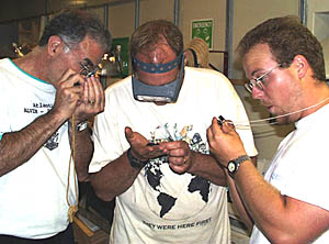 Mike Perfit (left), Bob “Yogi” Elder (center), and Erin Todd (right) carefully examine the glassy rocks recovered this evening. Mike and Erin are using hand-lenses that magnify about 8 times; Yogi has his special magnifying glasses on, which he usually uses to make repairs on tiny electronic components.