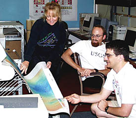 Uta Peckman finishes making a large multibeam bathymetry map, and studies it with Dan Scheirer (right) and Scott White in the Computer Lab. The map shows the changing water depths, and hence the seafloor’s elevation, in the area we have been surveying over the past few days. Uta, Dan, and Scott spend a lot of time each day making accurate maps that are used by the scientists and the person “flying” the DSL-120 or Argo II fish to tell if there is a hill or canyon ahead of the fish. When a hill is ahead, the fish has to be pulled up so that it doesn’t crash into it. If there is a canyon ahead, the fish is lowered to get a closer look at the bottom. 