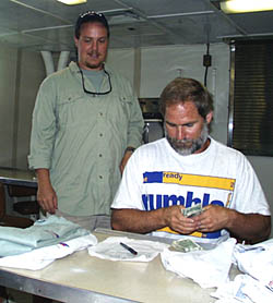 Saturday is also the day when ship’s business is taken care of, and Dave Murline sells R/V Melville T-Shirts to the science party. Here, Erin Todd stocks up on shirts to take home to family and friends. 