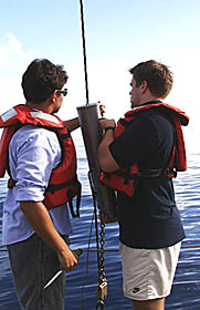 Jon Burgess (left) and Ben Wigham (right) take the pinger off the dredge wire. The pinger emits a 12 kiloHertz “ping” which bounces off the seafloor and comes back to the ship’s recorders in the Main Lab. The recorder shows the distance between the pinger and the seafloor; that tells us how high above the bottom we are. We usually put the pinger about 150 meters above the dredge. When the recorder shows that the pinger is about 50 meters above the bottom, we know we have the dredge and about 100 meters of the dredging wire on the bottom. As the ship moves forward slowly, the dredge is pulled along the bottom to scoop up rocks.
