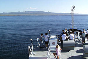 Members of the science team look at the view as Melville approaches Santa Cruz Island, one of the main islands in the Galapagos archipelago.