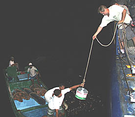 Tonight, we met up with a small boat from the Galapagos National Park on Isabella Island. They needed some supplies transported to them quickly, and Capt. Buck agreed to help. Here, Dave Murline lowers some barbed wire to the folks on the “panga” -- the small boat used for transport near to shore. The wire, the logs (already in the panga), and some tin roofing that we delivered will be used for a National Park construction project.