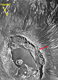 A vertical photograph of La Cumbre volcano on Fernandina Island. This was taken by the US Air Force in 1946 from an elevation of about 10,000 feet. Note that the caldera of the volcano has a lake in it. Air photographs taken later show that this lake disappeared sometime before 1960. Fernandina is the youngest island in the Galapagos Islands. There have been many eruptions over the last 50 years. Eruptions took place in 1959, 1968, 1982, 1988, and the most recent one occurred in 1995. These eruptions have greatly modified the shape and depth of the summit caldera. The 1968 eruption caused the caldera to subside, or sink, about 300 meters. The lighter patches in the photo are areas of older lava with more vegetation. The darker areas that form linear stripes coming out from the caldera are younger lava flows. 