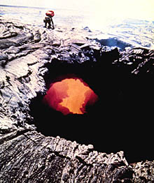 A photograph taken by the US Geological Survey on the Island of Hawaii showing a lava tube forming. The geologist in the background is collecting samples. Can you believe that only 8 meters below the cool lava surface that he is standing on, there is molten lava flowing through the tube! 