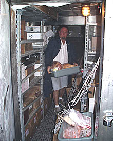 Dan carries some of the meat to be used in today’s meals out of the walk-in freezer. He is wearing a heavy, insulated coat because it is really cold in there.