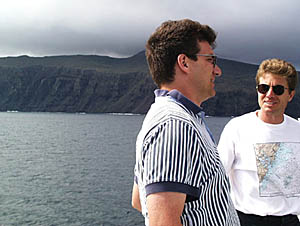 Dan Scheirer (left) and Captain Eric Buck taking in the view as R/V Melville steams past the west-facing cliffs of Pinzon Island this afternoon.