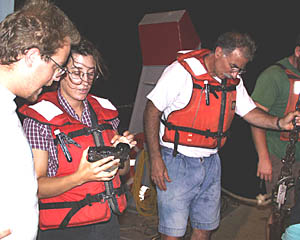 Clare Williams (center) shows Erin Todd (left) the glassy lobate lava recovered by the dredge.