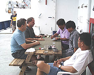 The ship’s crew relax during their nightly card game after dinner. 