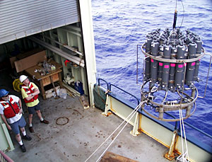  Scientists Marvin Lilley and Darryl Green watch as a crane hoists the CTD and water sampling bottles over Knorr’s starboard side. 
