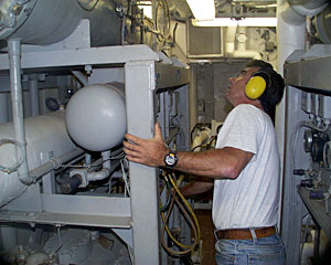 First Assistant Engineer Wayne Sylvia makes the rounds in the engine room, a hot, noisy -- and important place on the ship. Here reside all controls, from air conditioning to plumbing. “We are constantly checking the machinery,” Wayne said. “The ship is like a little city and we have to monitor for problems.” 