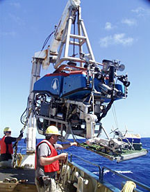 This view of ROV Jason going over the ship’s port rail shows the manipulator and basket on the front of the vehicle.  