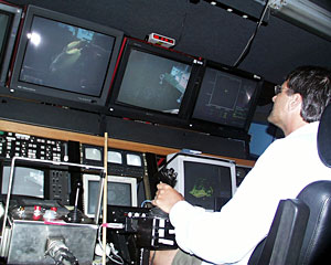 Expedition Leader Andy Bowen pilots ROV Jason from the control van. Scientists and the DSOG team rotate watches around-the-clock to make observations using Jason’s cameras. Inside the dark control van are 22 computer and television monitors. 