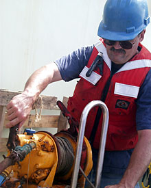  Seaman Bill Dunn uses a machine called a tugger to control a line steadying the elevator as it is hoisted on board Knorr. 
