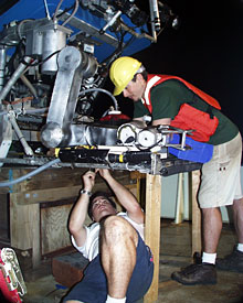  DSOG tech Mark Bokenfohr crawls underneath ROV Jason to secure cables, while fellow tech Fran Taylor assists. 