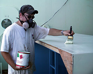 Wearing a mask to protect his lungs from paint fumes, Seaman Mike Doherty puts the finishing touches on the ship’s “pool.” 