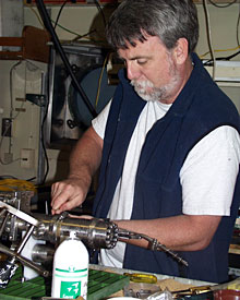 Chemist Eric Olson prepares a gas-tight fluid sample bottle to be lowered on the elevator tonight.  