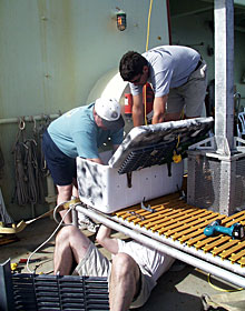 Scientists today began tearing down equipment, including the elevator. Wrestling to unbolt a sampling box are Tim Shank (in hat), Pete Collins and Robert Kunzig (under elevator).  