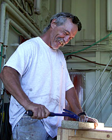 Seaman Kevin Butler takes screws and nails out of a board so it can be used for other projects on the ship.  