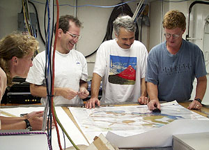  From left to right, Karen Harpp, Mark Kurz, Dan Fornari and Dennis Geist are reviewing the bathymetric map as they plan the sonar surveys. 