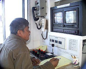  All the time the dredge is in the water, the winch controls must be manned. Here Eduardo Angeles, the Oiler, monitors the winch. 