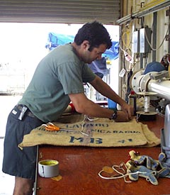 Josh Curtice prepares a burlap sack to go into the next dredge. The burlap is placed at the bottom of the chain bag to capture any small pieces of glass and rock that might otherwise fall through the netting that lines the dredge. 