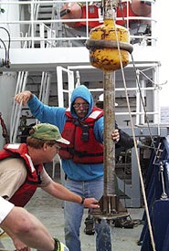  Today we collected samples using a rock core. This sampling device basically involved bashing a heavy steel pipe into the lava on the seafloor. Samples of the chipped volcanic glass are recovered in small metal cups that contain surfboard wax. When the core hits the ocean floor bits of rock, glass, and sediment stick in the wax. Here Denny Geist lends a helping hand as Gene Pillard, the Res. Tech., directs the recovery. 