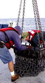 Gene Pillard (left), Res. Technician, and Denny Geist pull a rock sample out of the dredge. 