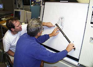  Mark Kurz (left) and Dan Fornari study the multibeam bathymetry map as it is being plotted to pick a position for the next dredge. 