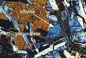  This is a thin section of diabase, a type of basalt that is coarse-grained; meaning it has lots of larger mineral crystals in it. It has more and larger crystals because it cooled slower than most pillow basalts, which are finer-grained. The arrows show olivine and plagioclase. Photomicrograph by Mike Perfit, U. Florida. 