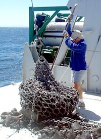  Dan Fornari uses a crowbar to help get large rocks out of the dredge bag. 