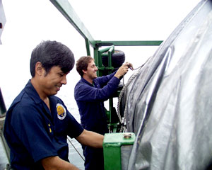 Steve Tottori and Todd Ericksen (background) put a cover over the MR1 sidescan sonar, to prepare it for shipping. 