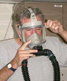 John Lupton tightens the straps on the mask of the Emergency Breathing Apparatus to make sure it fits snugly.