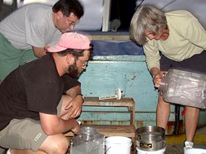  Jonathan Eisen (hat) and Anna-Louise Reysenbach filter a “slurp” sample collected by Alvin to extract any particles or small animals. Co-Chief Scientist Steve Hammond watches in the background.