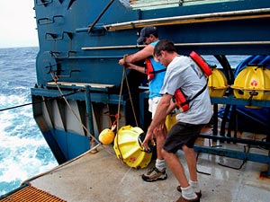 Alvin Technicians Bruce Strickrott, left, and Gavin Eppard preparing to drop transponders into the sea. 