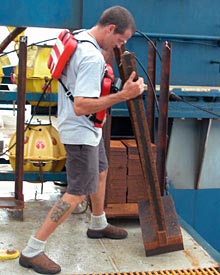 Alvin Technician Gavin Eppard, preparing to drop a weight that sinks to the bottom of the ocean. The attached transponder floats 160 to 185 meters above it."