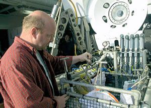 Scientist Tim Shank inspects Alvin's dive basket, which is used to transport samples from below the ocean surface back to the ship. Alvin uses its two mechanical arms to collect organisms in the white mesh nets visible in this photograph. The sub then dumps those nets into its main basket. 