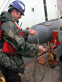 Soaked but happy after a somewhat rough ride in the Avon, Able Seaman Jerry Graham coils the boat's lines and takes a much deserved breather.  