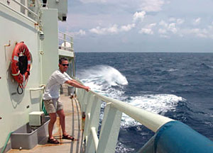 Science writer Joe Appel holds tight to the railing off the port side of R/V Atlantis. Winds were gusting at more than 30 knots, and swells were getting to 12 feet high. Under conditions such as these, deploying Alvin is not an option. 