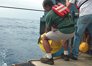 Alvin technician Noel Masias drops a transponder off the stern deck of R/V Atlantis as weather conditions improved in the late afternoon. 